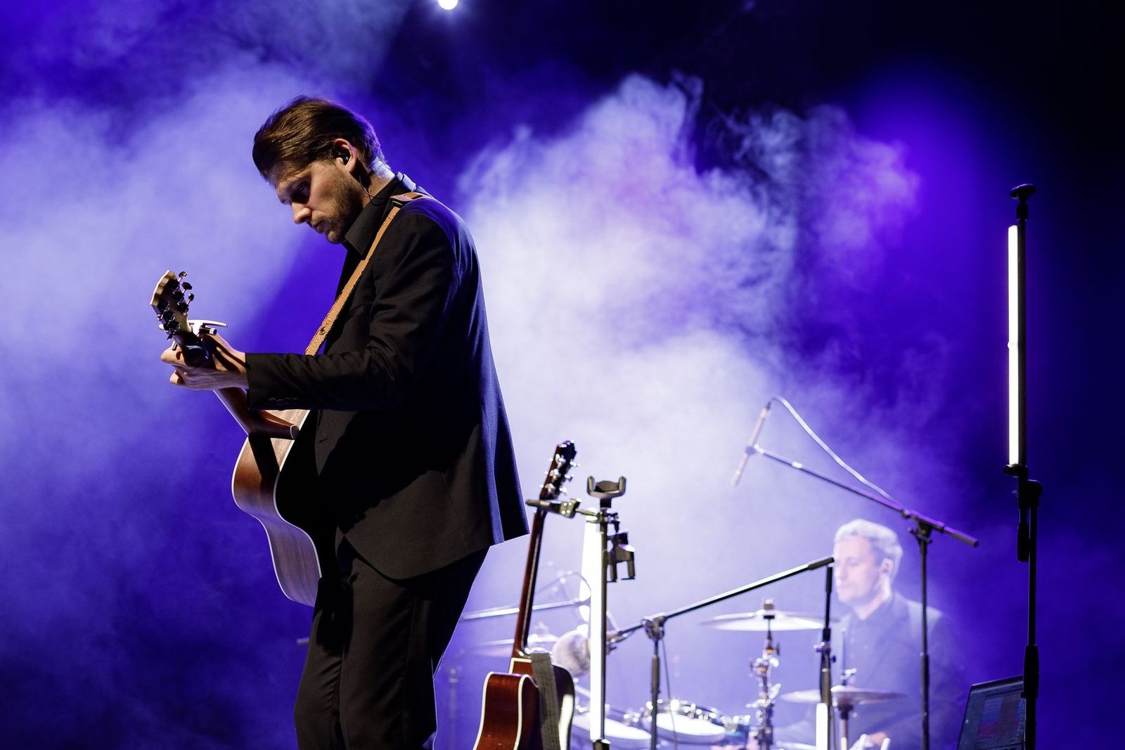 Justinas Stanislovaitis groja gitara scenoje šviesų ir dūmų fone