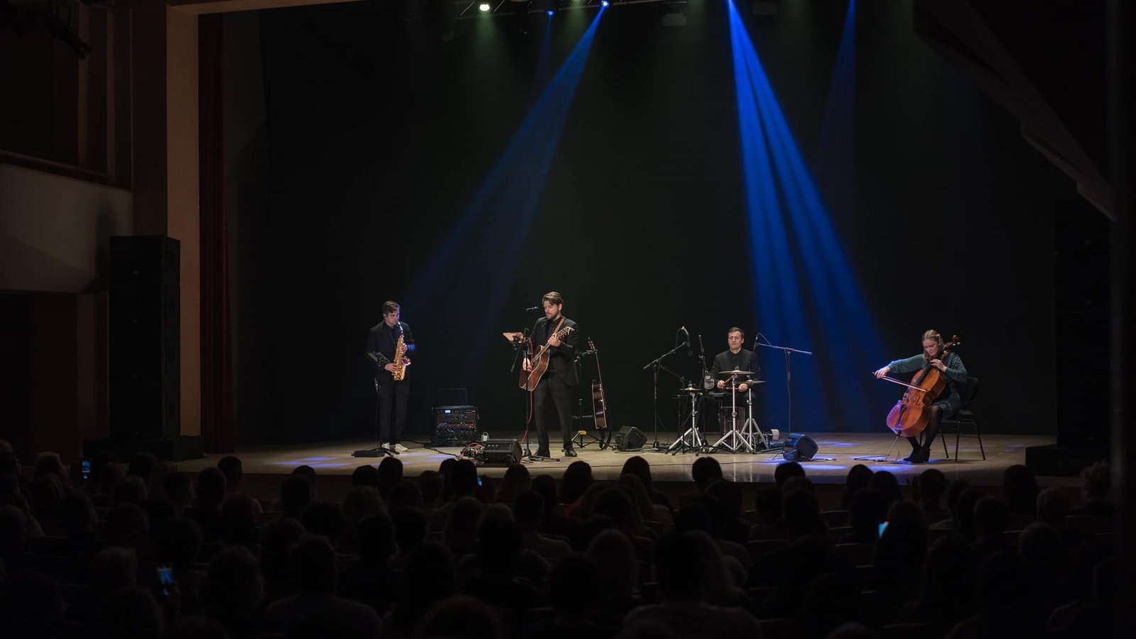 The band in concert in a large hall under blue light