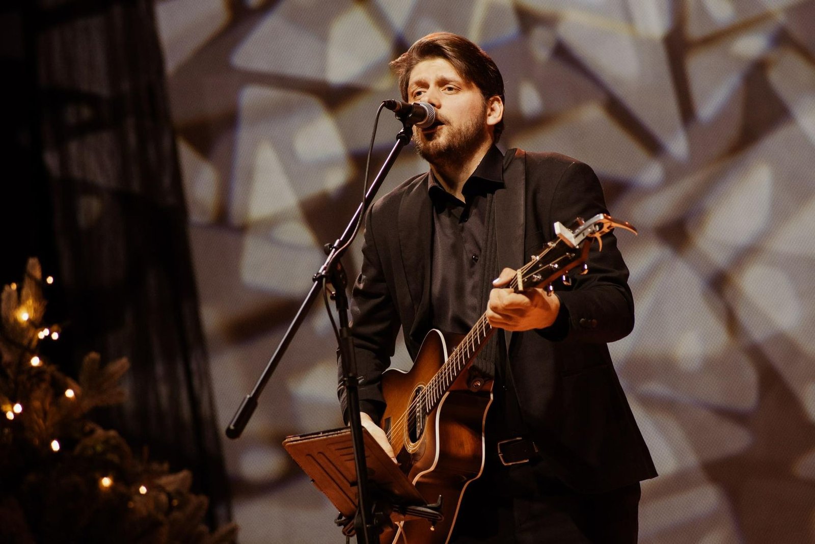 Justinas Stanislovaitis singing with a guitar in warm evening light
