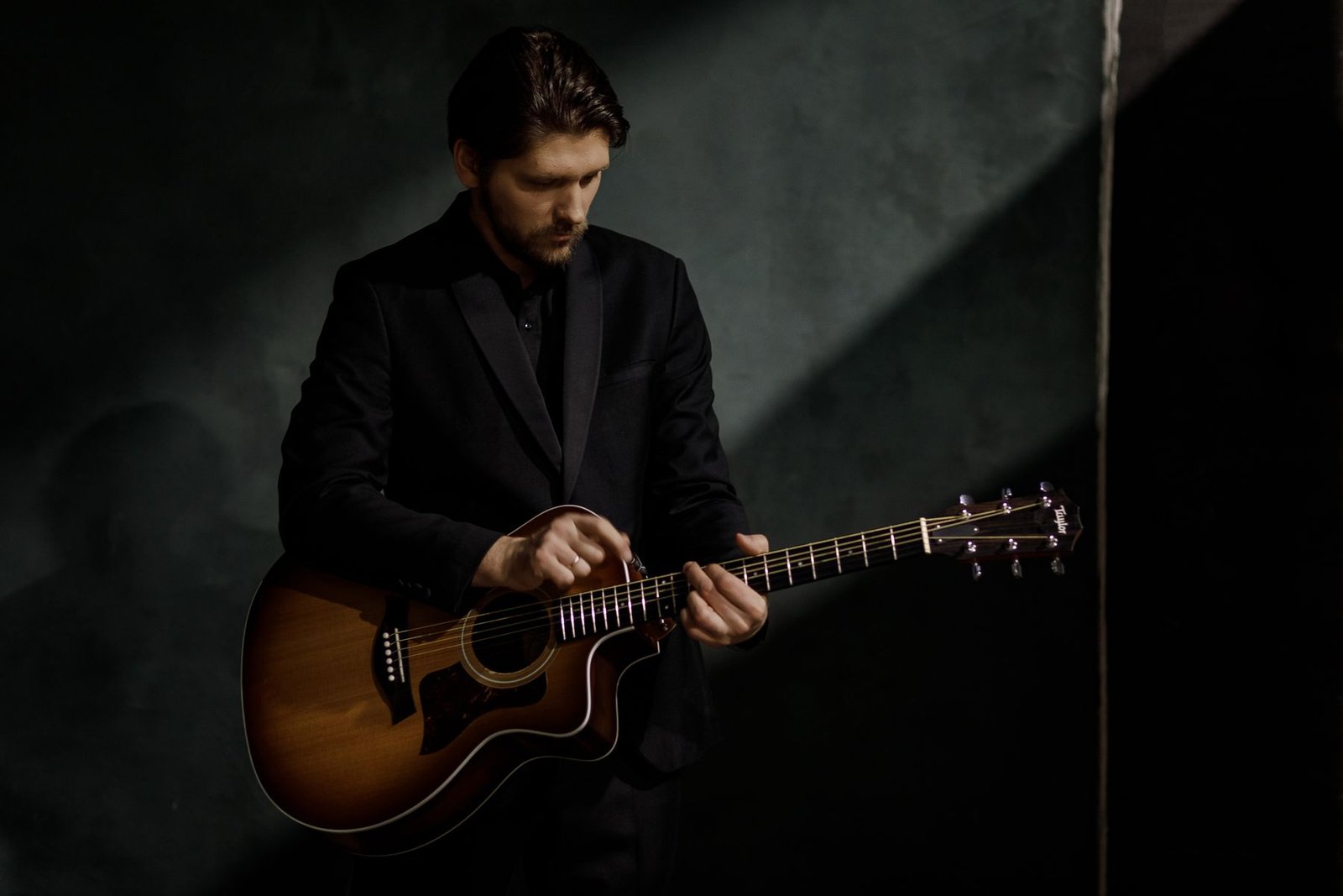 Studio portrait of Justinas Stanislovaitis with a guitar on a dark background