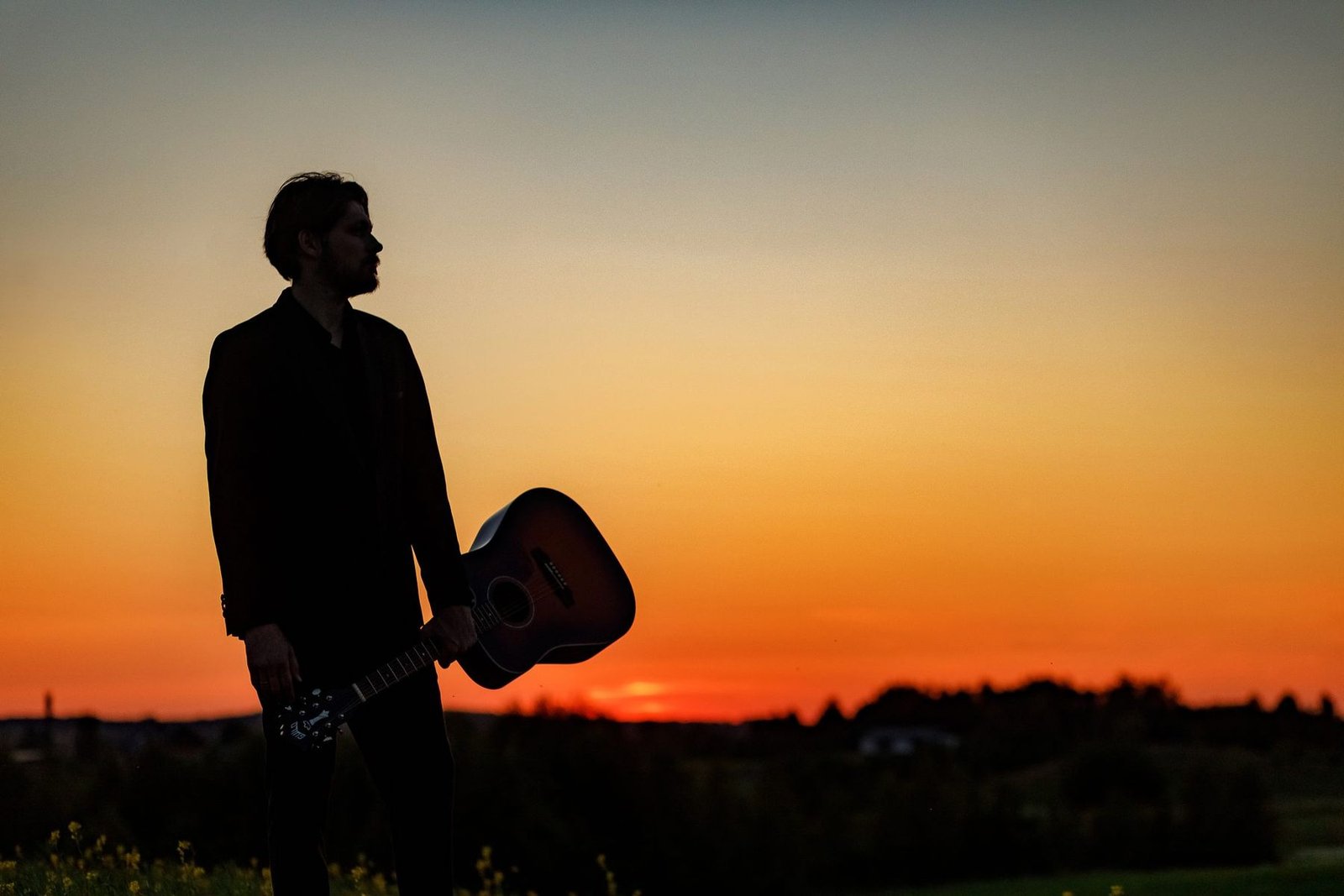 Justinas Stanislovaitis with a guitar against the sunset