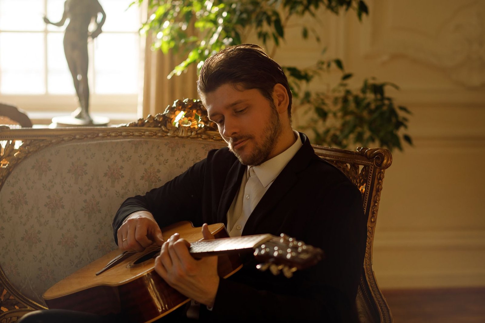 Justinas Stanislovaitis playing guitar in a manor interior